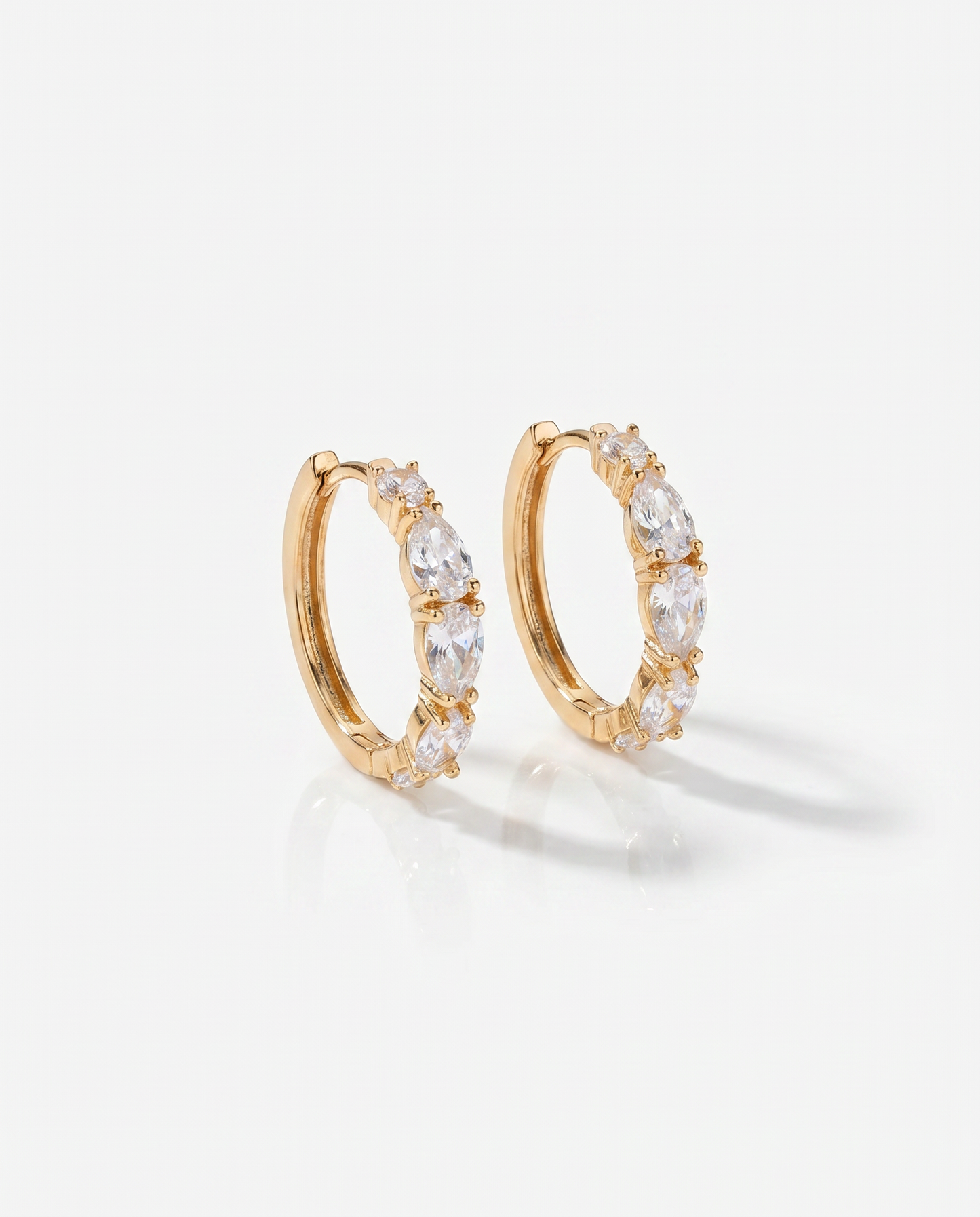 Gold hoop earrings with clear stones on a light gray background