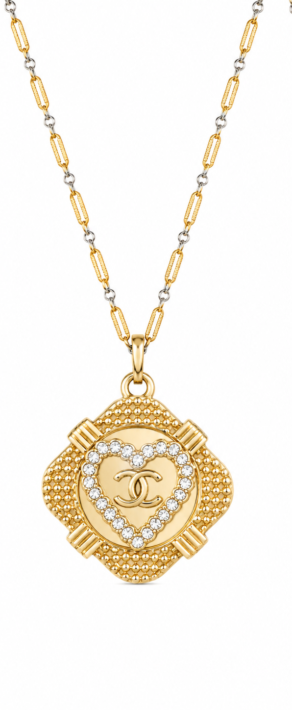 Two views of a gold-tone Chanel necklace with a clover-shaped pendant. One side shows the front with a central heart-shaped crystal border and interlocking CC logo, while the other side shows the textured back with the Chanel name engraved.