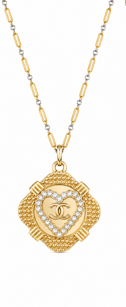 Two views of a gold-tone Chanel necklace with a clover-shaped pendant. One side shows the front with a central heart-shaped crystal border and interlocking CC logo, while the other side shows the textured back with the Chanel name engraved.