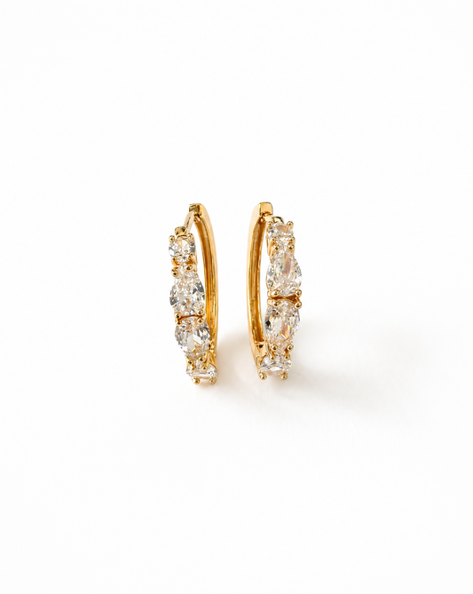Gold hoop earrings with clear gemstones on a white background