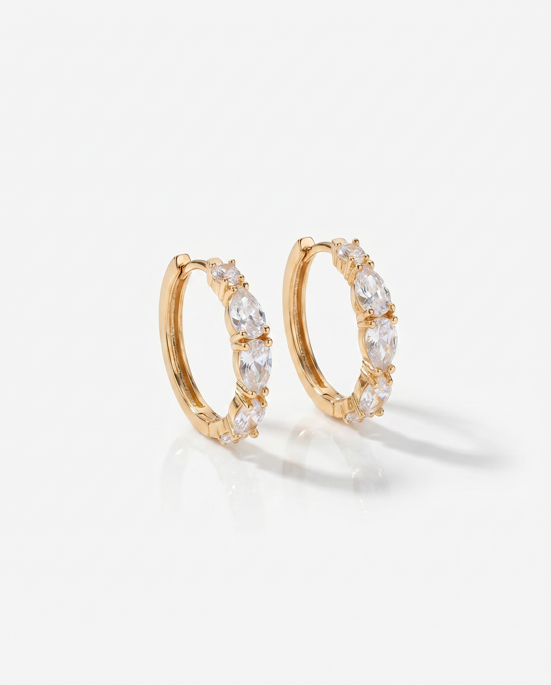 Gold hoop earrings with clear stones on a light gray background