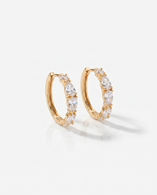 Gold hoop earrings with clear stones on a light gray background