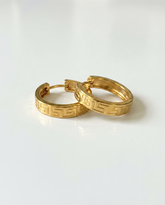 Gold hoop earrings with a geometric pattern on a white background